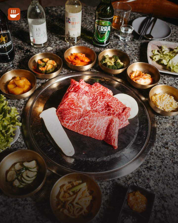 Marbled beef on a hot stone grill with Korean side dishes